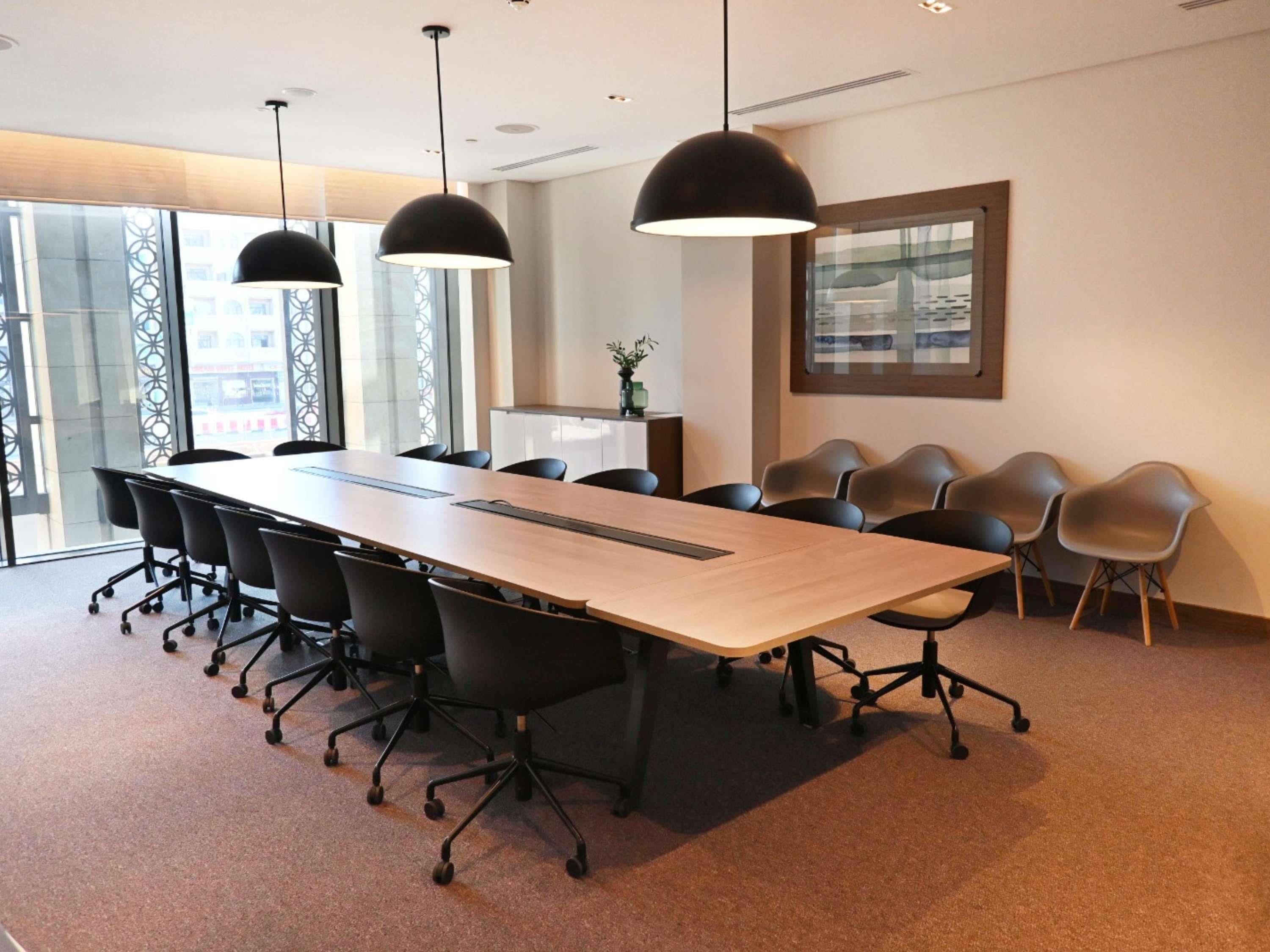 A conference room with a long table, black chairs, and pendant lighting.