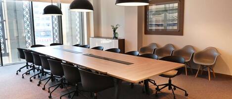 A conference room with a long table, black chairs, and pendant lighting.