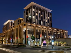 A modern building with a prominent entrance, large windows, and a flag. - Mercure Dubai Gold District (Dubai)