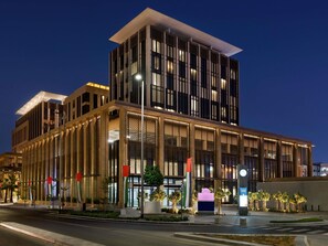 A modern building with a prominent entrance, large windows, and a flag. - Mercure Dubai Gold District (Dubai)