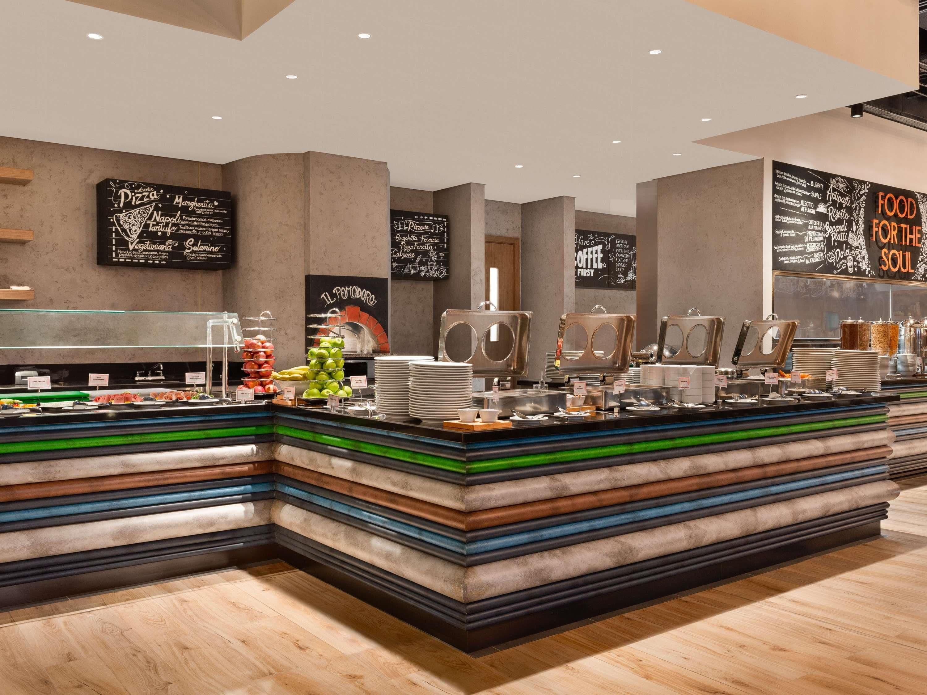 Un bar à petit-déjeuner moderne proposant une grande variété d’aliments, notamment des fruits, des viennoiseries et des machines à café.