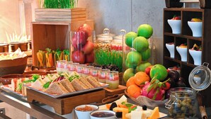 A buffet with various food items, including sandwiches, fruits, and condiments.