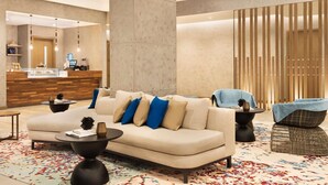 A modern lobby with a sofa, coffee table, and a reception desk.