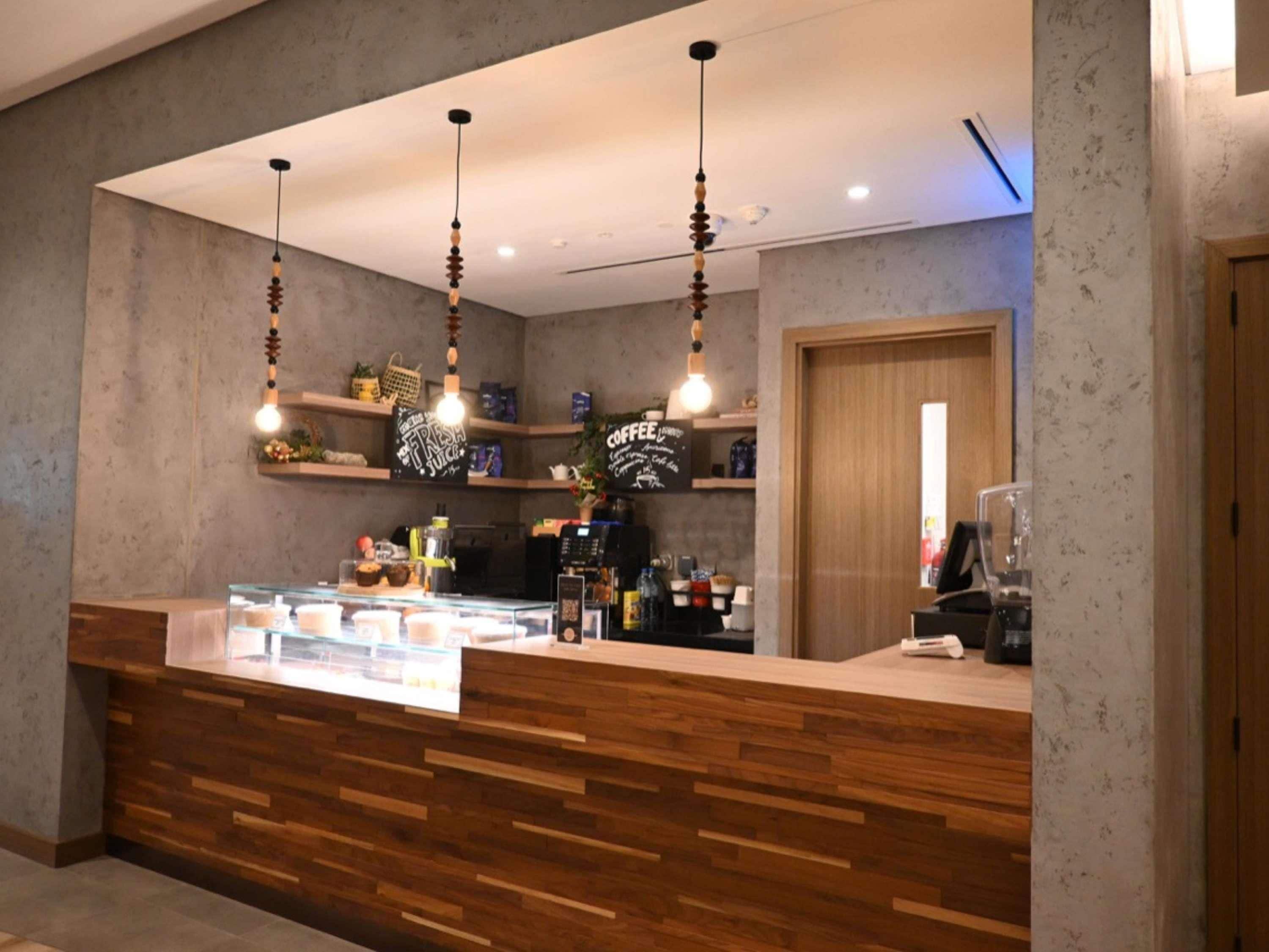 Una moderna zona de recepción con mostrador de madera, lámparas colgantes y una estación de café.