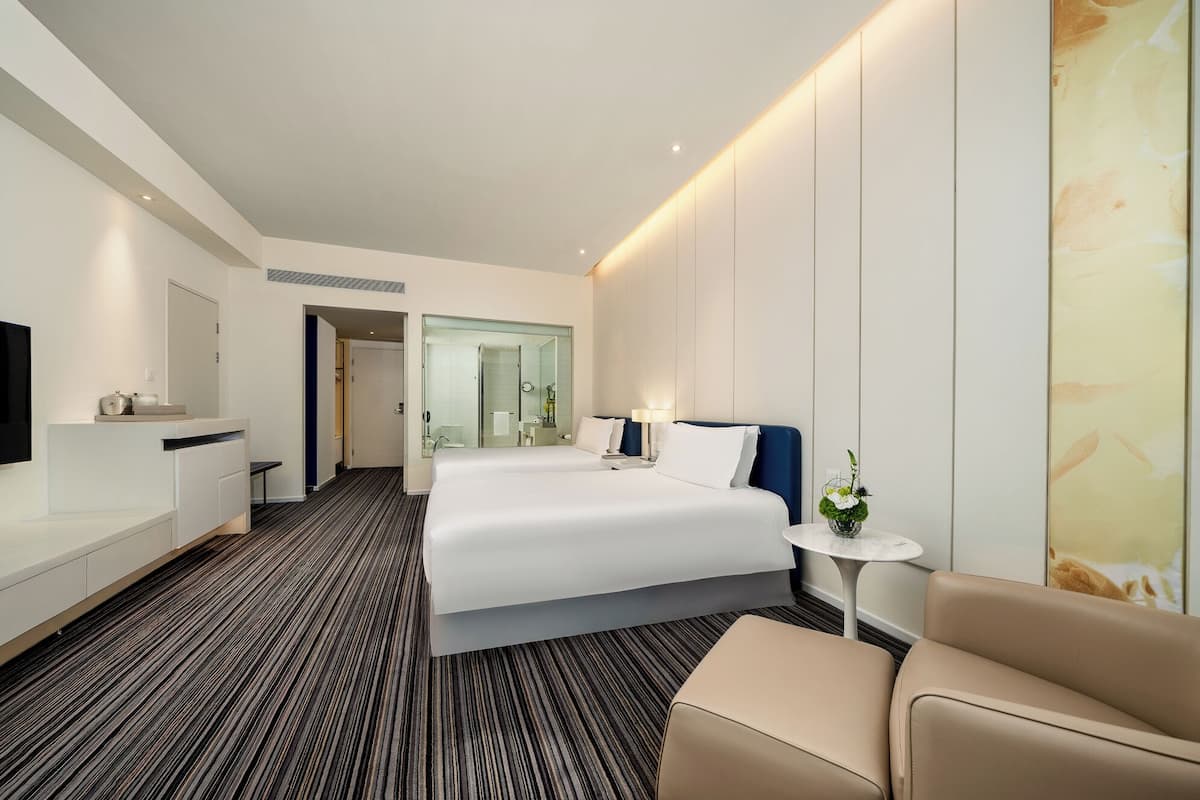 Ein modernes Hotelzimmer mit einem großen Bett, einem Nachttisch, einem Fernseher und einer Sitzecke.