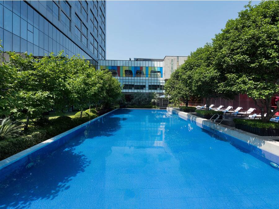 Una piscina con sillas de descanso y un edificio al fondo.