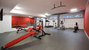 A modern gym with red and black equipment, a bench press, treadmills, and a rowing machine. - RentPlanet - Bliżej Morza (Kolobrzeg)