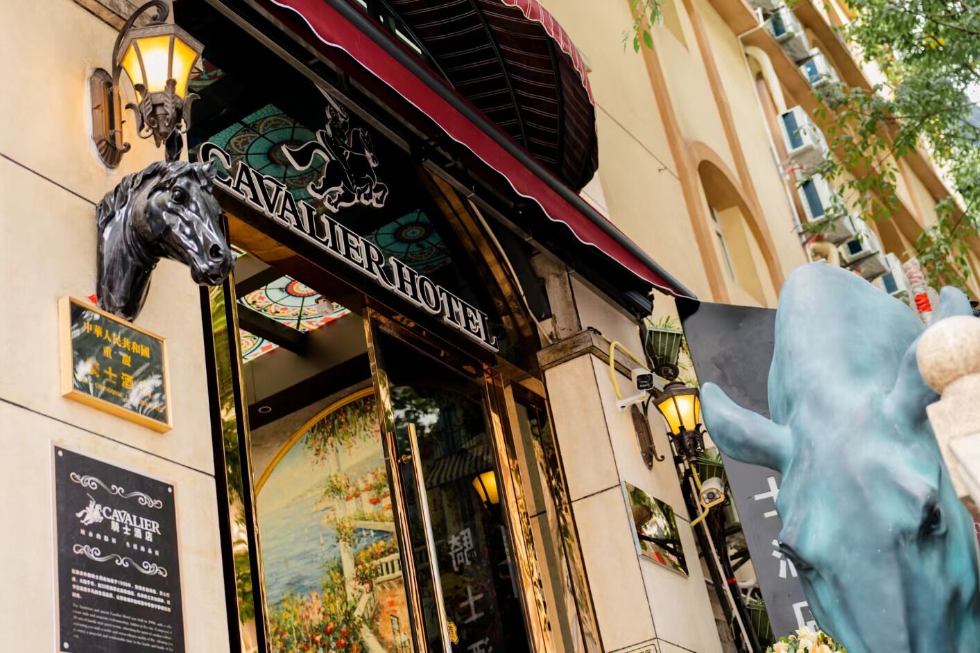 The exterior of the Cavalier Hotel with a horse statue, a red awning, and a signboard.