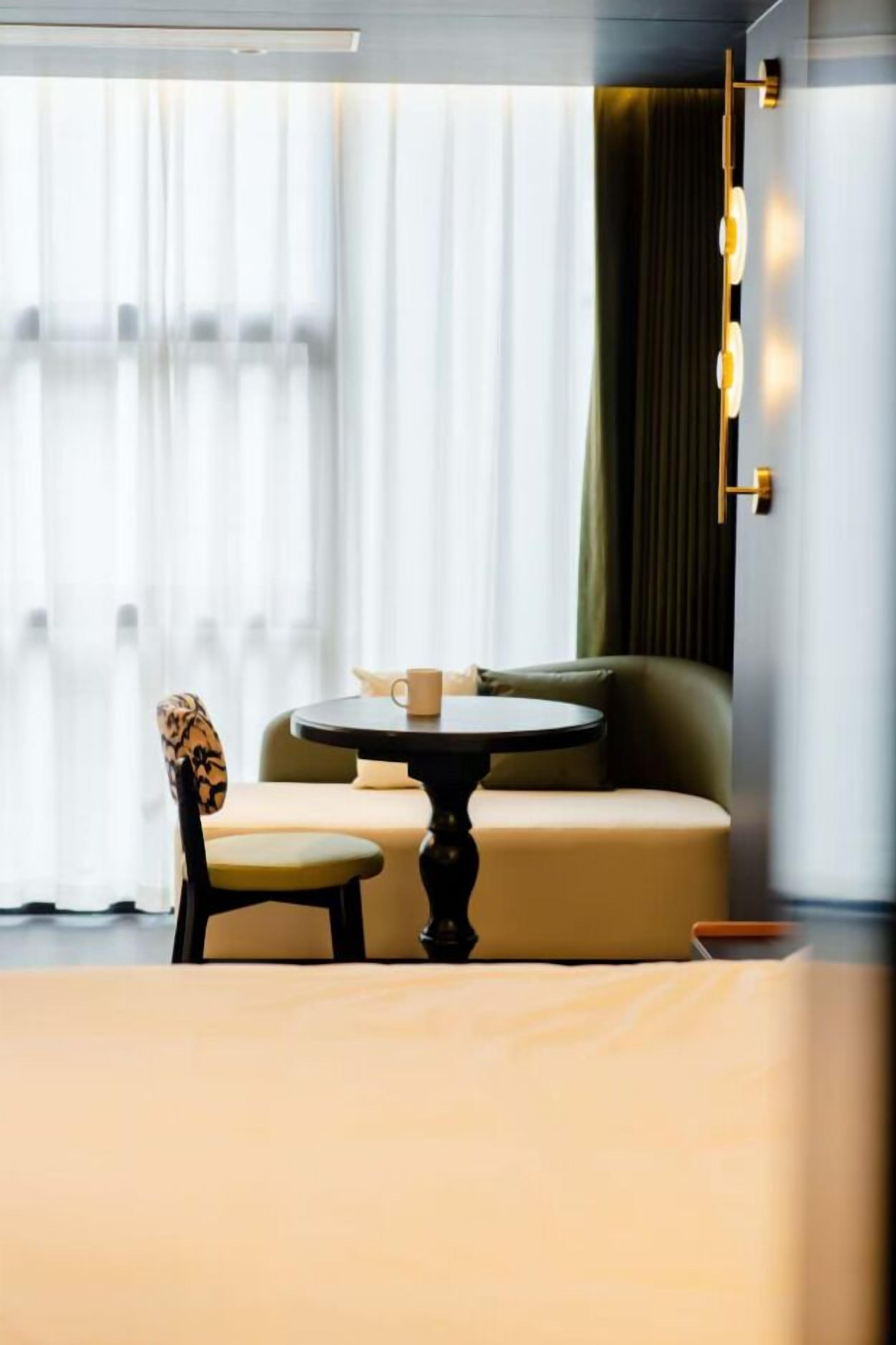 Une chambre d’hôtel moderne avec une table ronde, un canapé et un fauteuil.