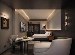 Une chambre d’hôtel moderne, équipée d’un lit, d’un coin salon avec une table et d’œuvres d’art accrochées aux murs.