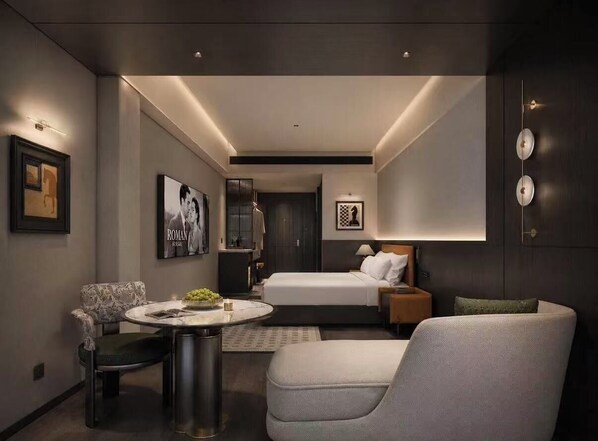A modern hotel room with a bed, a seating area with a table, and artwork on the walls. - Cavalier Hotel (Chongqing)