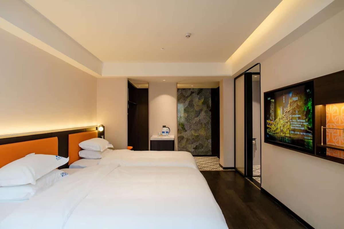 A hotel room with a bed, a desk, a bathroom, and a TV.