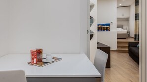 A modern hotel room with a dining area, a bed, and a view of a cityscape. - Hermes Apartment with private parking (Trieste)