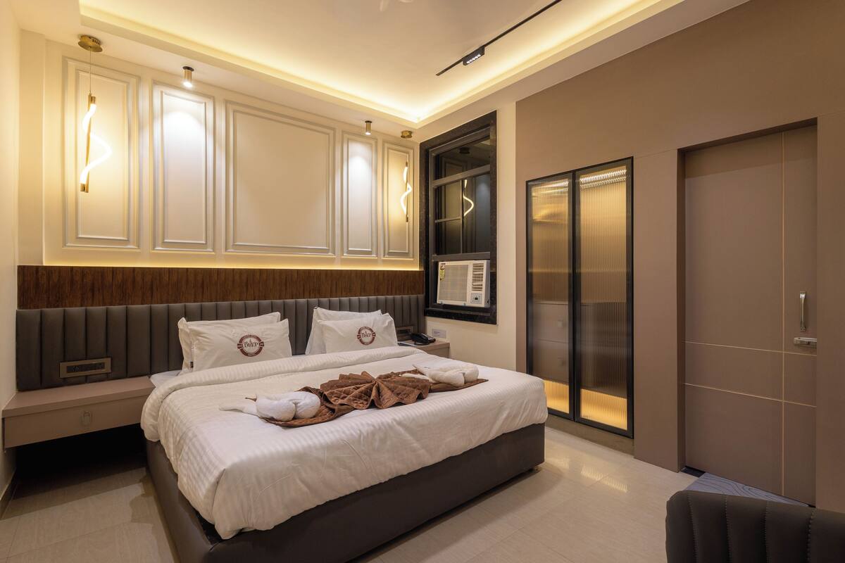 A modern bedroom with a large bed, built-in headboard, bedside tables, and a wardrobe.