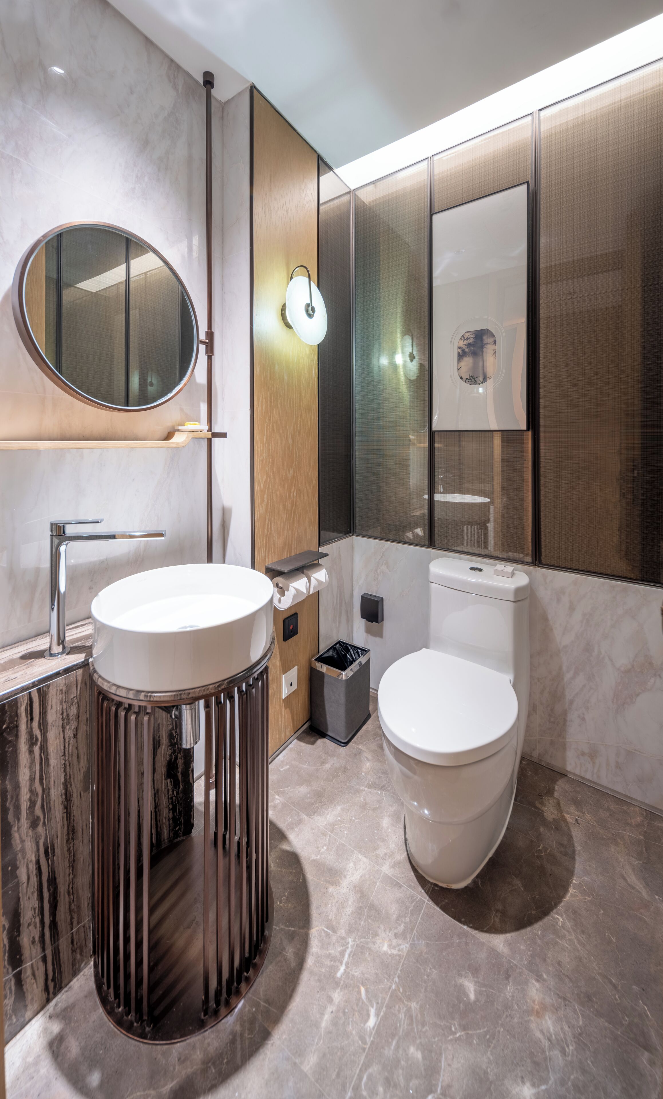 Een moderne badkamer met een ronde spiegel, een wastafel en een toilet.