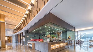 Um lobby de hotel moderno com área de bar central, piso de mármore e teto alto com lambris de madeira.
