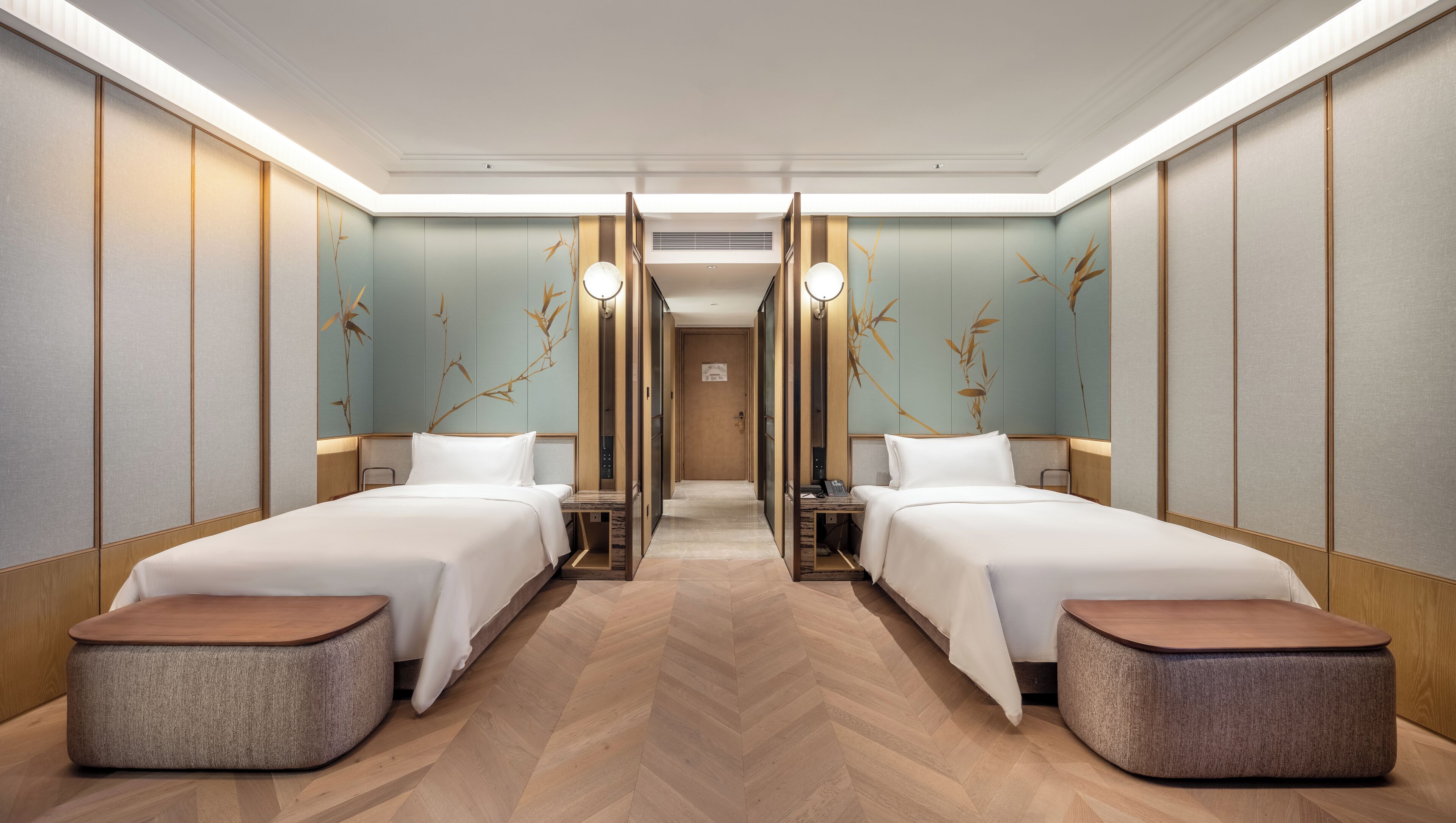 Ein Hotelzimmer mit zwei Betten, Holzboden und einer Wand mit Bambus-Kunstwerken.