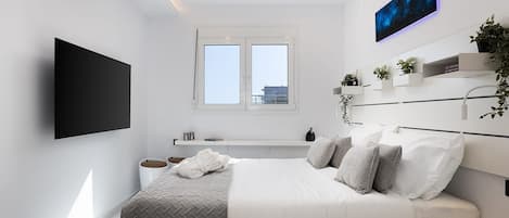 A modern bedroom with a bed, a flat-screen TV, a window, and a wall-mounted shelf with plants.