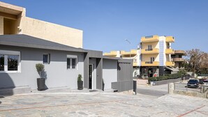 Un edificio moderno con fachada gris, una entrada pequeña y un patio empedrado de piedra.