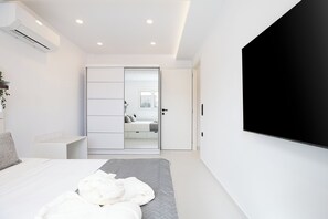 Een moderne slaapkamer met een bed, een televisie, een airconditioner en een schuifdeurkast.