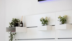Un dormitorio moderno con cama, almohadas y estanterías murales con plantas.