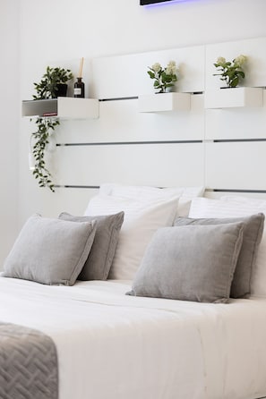 A modern bedroom with a bed, pillows, and wall-mounted shelves with plants.