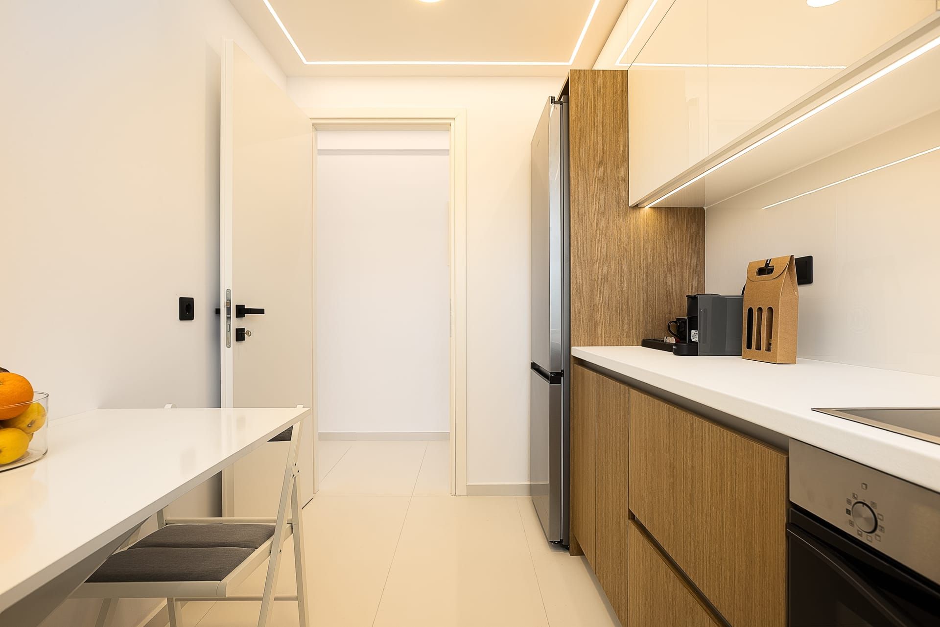 A modern kitchen with a built-in refrigerator, a coffee maker, and a paper towel dispenser on the countertop.