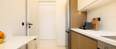 A modern kitchen with a built-in refrigerator, a coffee maker, and a paper towel dispenser on the countertop.
