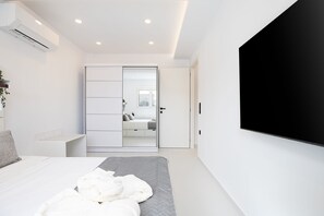 A modern bedroom with a bed, a large mirror, and a TV mounted on the wall. - Maxi Suite 75 with Jacuzzi (Gazi)