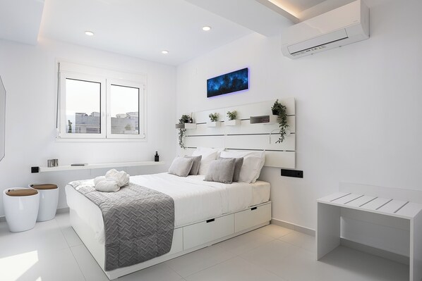 Een moderne slaapkamer met een bed, nachtkastjes, een raam en een airconditioner.