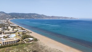 Vista costera con playa, edificios y un paisaje montañoso al fondo.