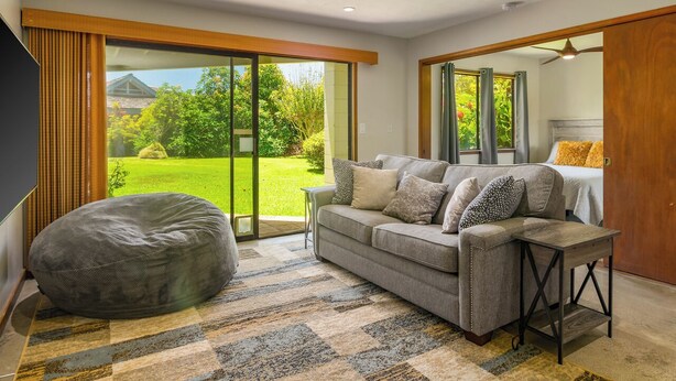 Un salon moderne avec un canapé gris, un fauteuil en forme de poire et un tapis à motifs.