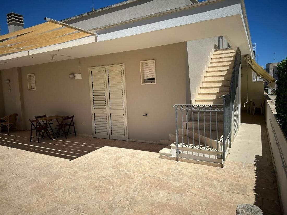 A residential building with a covered patio, a staircase, and a dining area.