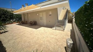 A two-story house with a tiled patio, a staircase, and a small outdoor seating area. - Andromeda Rooms  in Otranto (Otranto)