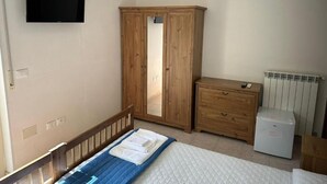 A bedroom with a bed, a wardrobe, a dresser, a television, and a radiator. - Andromeda Rooms  in Otranto (Otranto)