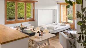Quarto moderno com cama, mesa de jantar e cozinha.