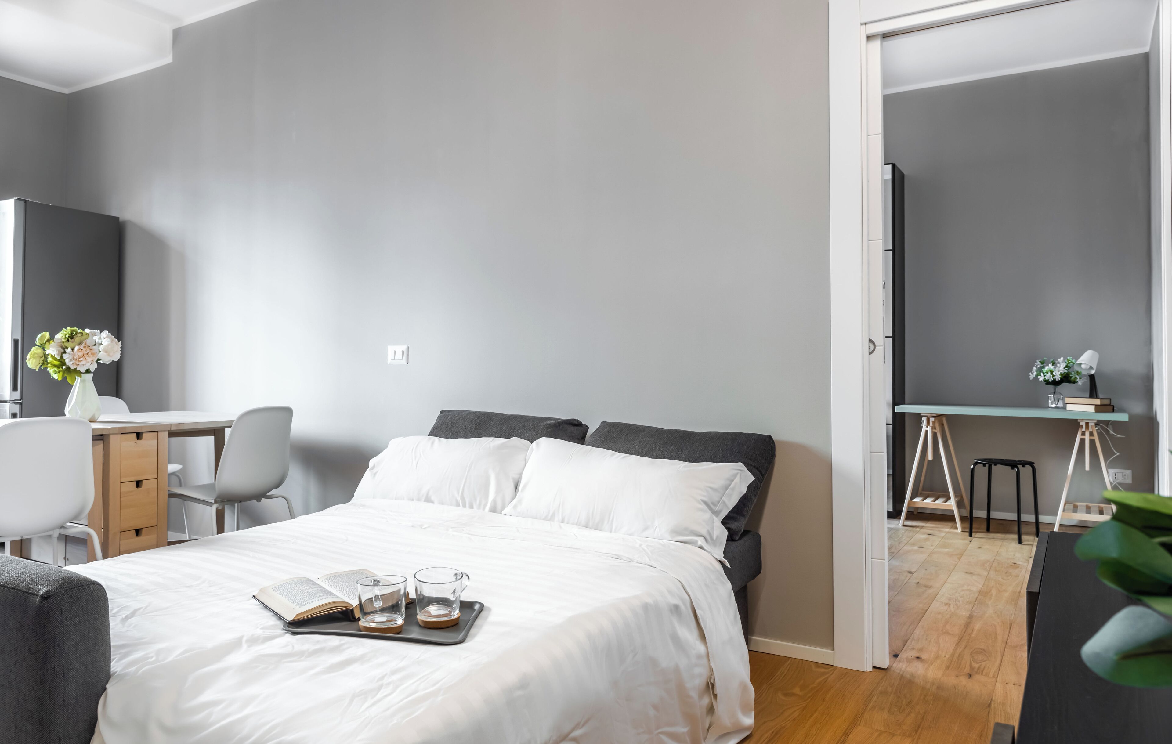 A modern bedroom with a bed, bedside table, and a desk area.