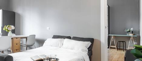 A modern bedroom with a bed, bedside table, and a desk area.
