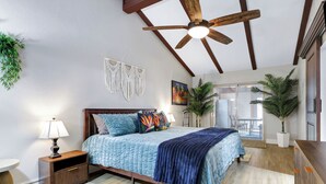 A bedroom with a bed, wooden headboard, ceiling fan, macrame wall decor, and potted plants. - Ultimate Retreat | Game Room Fire Pit BBQ Office (San Antonio)