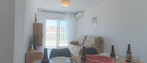 Un comedor con una mesa para dos, un sofá y un balcón con vistas.