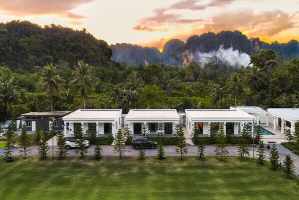 A modern resort with multiple white buildings, a swimming pool, and a lush green landscape with palm trees. - Tarn Villa Krabi (Krabi)