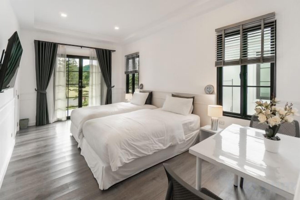 Un dormitorio con dos camas, un escritorio y una ventana con contraventanas.