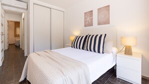 A bedroom with a bed, nightstands, a wardrobe, and two wall art pieces.