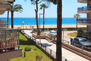 Un hôtel situé sur la côte, offrant une vue sur la plage, les palmiers et un espace de stationnement.