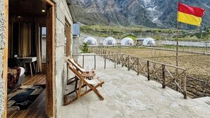 En bygning med træinteriør, en balkon med stol og bord, samt udsigt til bjerge.