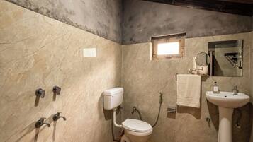 A bathroom with a shower, toilet, sink, and wooden floor.