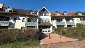 A row of modern two-story residential buildings with balconies and a paved walkway. - Pet-friendly one-room vacation apartment at the spa gardens (Bad Rodach)