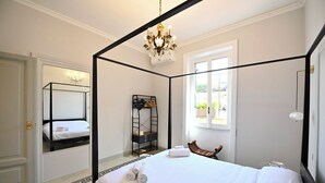 A four-poster bed with white linens, a chandelier, a wooden bench, and a ladder against the wall. - Imperium penthouse with terrace (Roma)