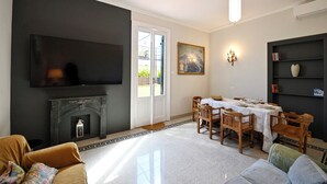 A living room with a fireplace, a dining table set for four, and a television mounted on the wall. - Imperium penthouse with terrace (Roma)