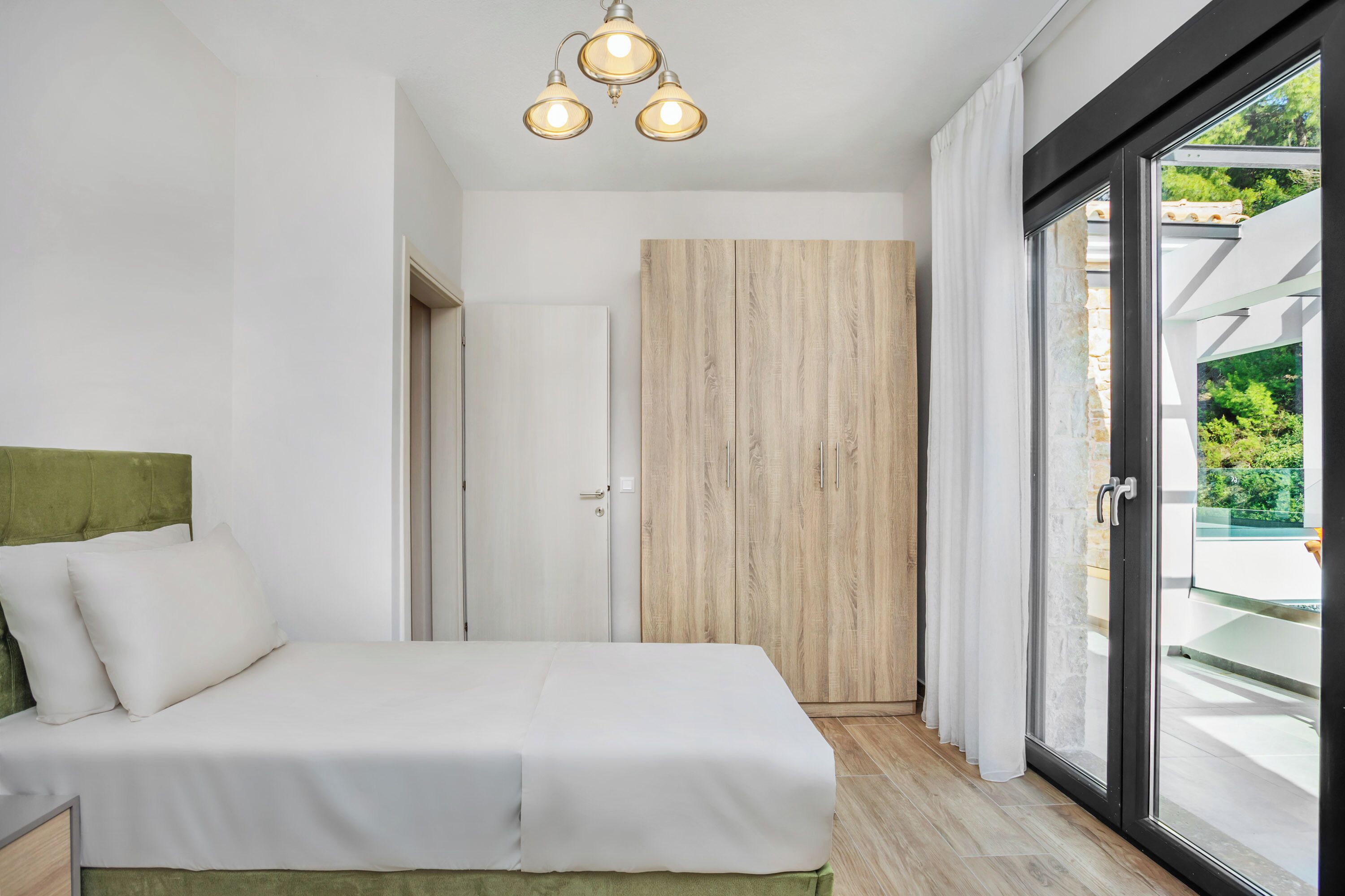 Une chambre moderne avec un lit, une armoire en bois et une porte-fenêtre coulissante donnant sur un espace extérieur.